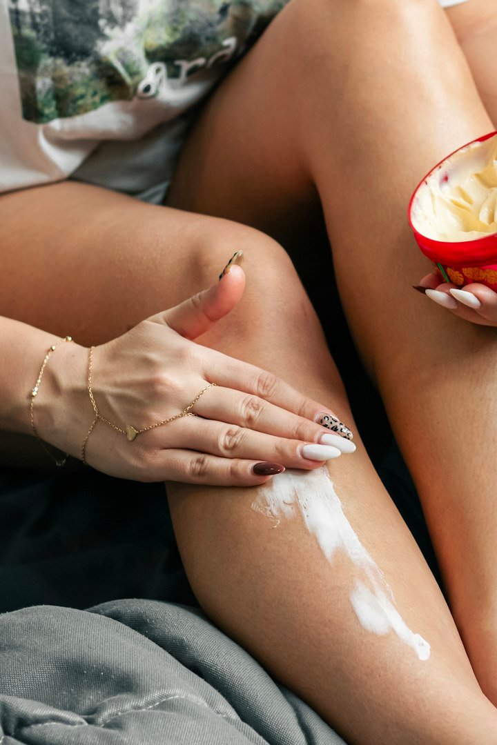 Mains appliquant une crème sur une jambe