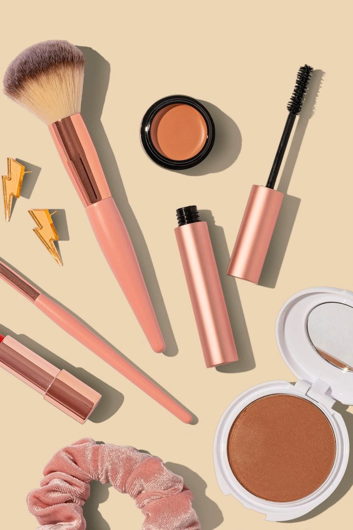 Pinceaux, mascara et poudres sur fond beige