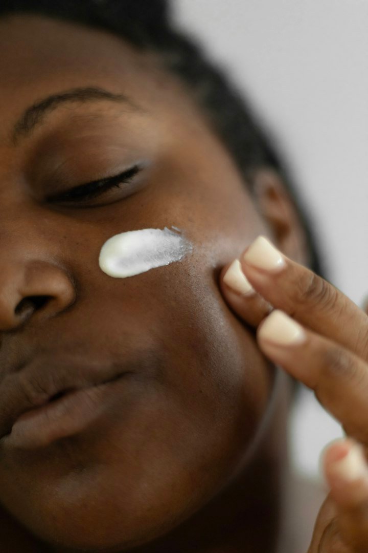 Femme appliquant une crème sur sa joue