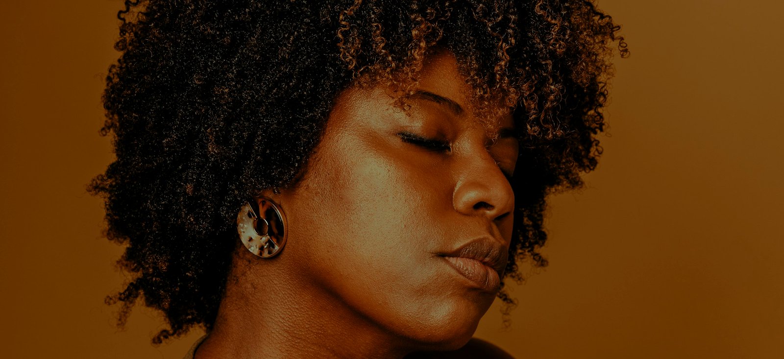 Portrait d’une femme aux cheveux bouclés dans une lumière ambrée